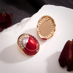 Macro view of vintage oval earrings with red and white resin inlay and crystal rhinestones