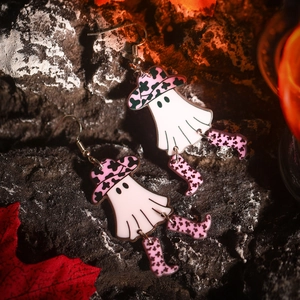 Close-up of Halloween ghost earrings with pink cowboy hats and dangling boots on black rock