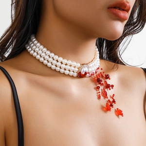 Macro shot of gothic three-layer pearl choker with red tassel drops and crystal gemstone