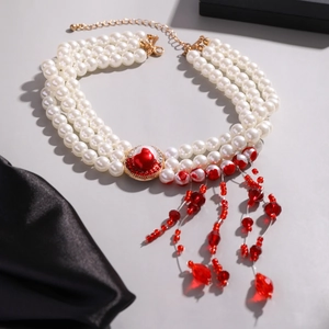 Detail of gothic pearl choker featuring red gemstone center and blood-drop tassels