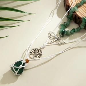 Detail einer Boho-Halskette mit Libelle, Lebensbaum und grünem Steinanhänger in Makrooptik