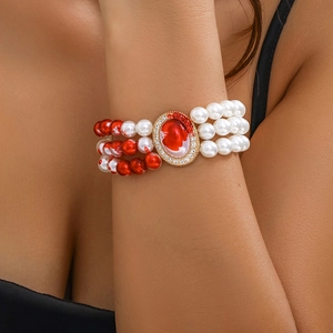 Detailed shot of triple-layer pearl bracelet with red marble beads and rhinestone centerpiece