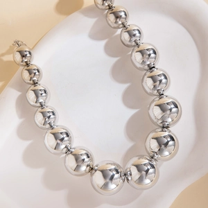 Détail des grosses perles argentées d'un collier de style industriel moderne et chic