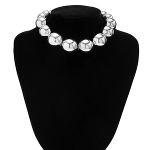 Vue macro d'un collier de perles argentées polies sur un support en velours noir