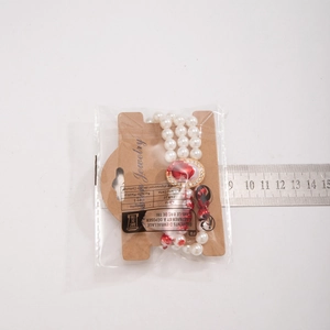 Macro shot of gothic pearl choker with red heart pendant inside packaging with ruler