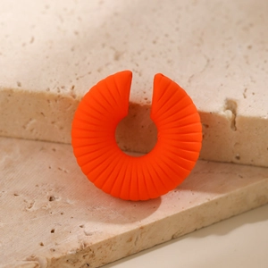 Macro di orecchino a C arancione vivace con trama a coste su pietra naturale beige