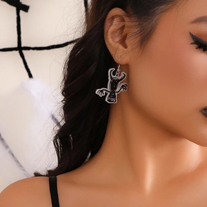 Close-up of a cartoon monster acrylic hook earring with dark goth style on model ear