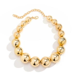 Gros plan de grandes perles dorées polies et fermoir mousqueton réglable sur le collier