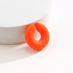Dettaglio di un ear cuff arancione acceso a forma di C con fine texture a coste a spirale