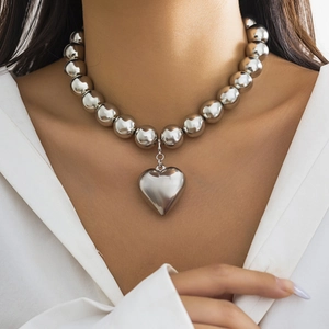 Punk silver bead necklace with large polished heart pendant on a female model