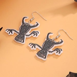 Detail of acrylic Halloween drop earrings with cartoon monster on orange background