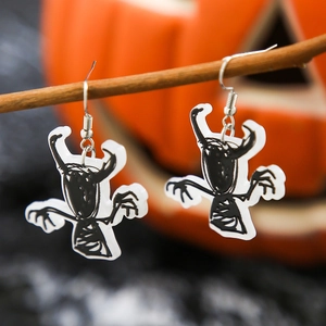 Detail of acrylic Halloween earrings with hand-drawn monsters on a rustic branch