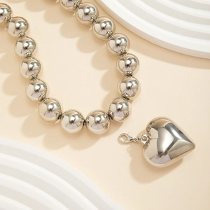 Close-up of silver punk choker featuring large metal beads and a heart pendant with clasp