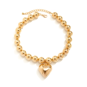 Close-up of golden beaded collar necklace featuring a large polished heart pendant