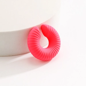 Dettaglio dell'orecchino a clip in silicone rosa acceso con sottili scanalature