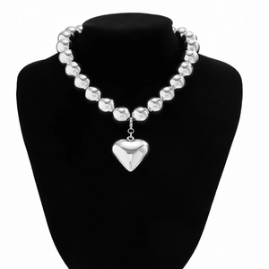 Close-up of polished silver metal beads with a large heart pendant on a display