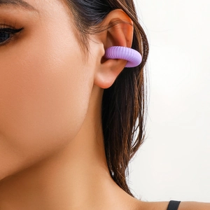 Primo piano di un ear cuff viola testurizzato con design a costine sul cartilagine dell'orecchio