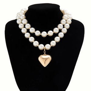 Detail of double-layer pearl necklace featuring a large polished gold heart pendant