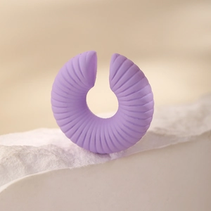 Dettaglio dell'orecchino a clip lilla con trama a spirale su base in pietra bianca