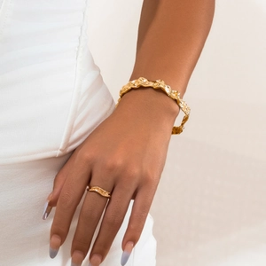 Detail van een gouden lava-armband en ring met gegolfde textuur en micro-diamanten