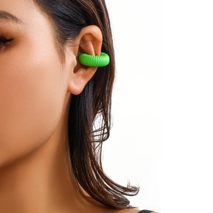 Dettaglio macro di un earcuff verde fluo con trama a coste sottili indossato sul lobo