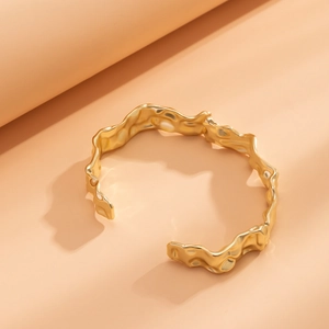 Macro-opname van gouden lava-textuur armband met onregelmatige gehamerde metalen golven
