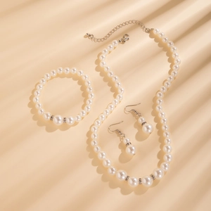 Gedetailleerde set van gelaagde parelketting, armband en oorbellen op elegante beige achtergrond
