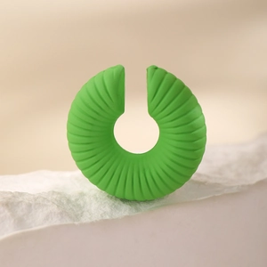 Ear cuff verde minimalista con scanalature radiali su una base di pietra naturale