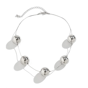 Gros plan des perles en métal poli sur un collier choker de style punk minimaliste
