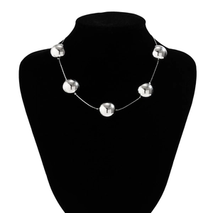 Détail de perles métalliques argentées sur un collier sur un support en velours noir