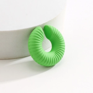 Dettaglio dell'orecchino a clip verde a forma di C con superficie rigata e finitura opaca