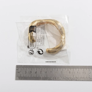 Detail van een goudkleurige open armband met gehamerde textuur en 7 cm diameter