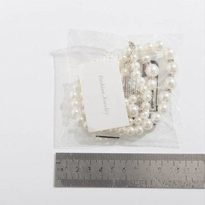 Detail van gelaagde parelketting met kristallen afstandhouders en liniaal voor de maat
