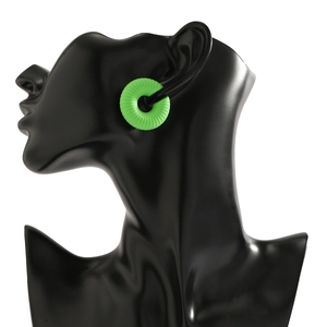 Dettaglio macro di earcuff verde brillante a forma di C con texture a spirale su modello