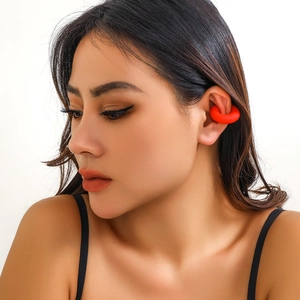 Primo piano di un ear cuff rosso con trama a spirale indossato da una modella