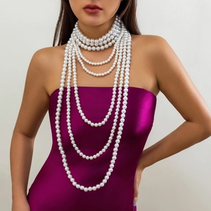 Detailopname van meerlaagse parelketting op model in paarse satijnen jurk