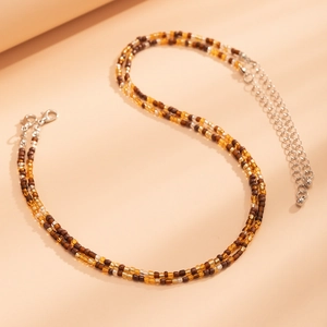 Detailed close-up of double-layered beaded necklace with amber glass beads and silver lobster clasp