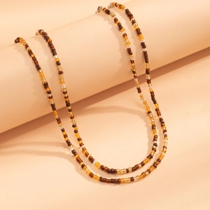 Detail of amber and beige beads necklace draped on a cylindrical display stand