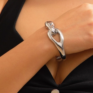 Dettaglio di un bracciale a fascia in metallo lucido argento con design astratto