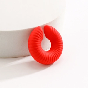Dettaglio di un ear cuff rosso opaco con superficie a coste a spirale per orecchio