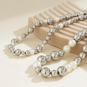 Vue détaillée des perles argentées polies et perles blanches sur un collier à couches