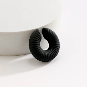 Vista dettagliata dell'ear cuff nero opaco a spirale su un espositore bianco minimal