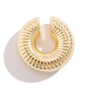 Vista macro di un earcuff dorato con texture a spirale lucida su sfondo bianco