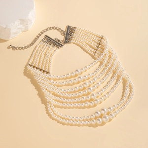 Detail van meerlaagse barokke parelketting met zilveren karabijnsluiting op een beige achtergrond