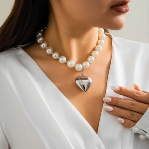 Detail of elegant pearl necklace with large beads and polished silver heart pendant