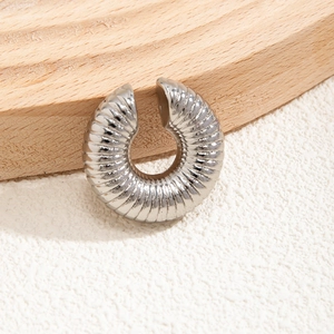Macro di orecchino a clip a spirale in argento su base in legno con luci calde e soffuse