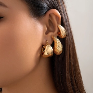 Nahaufnahme eines Modells mit einem 3-teiligen goldenen Tropfenohrring-Set mit Hammerschlag