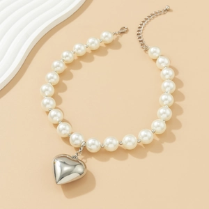 Close-up of pearl necklace featuring a large polished silver heart pendant and clasp