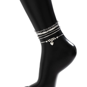 Detail of 5-piece silver heart punk anklet set on foot model with snake and bead chains