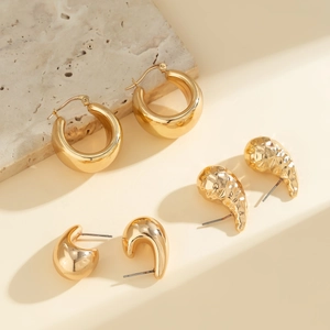 Detailansicht goldener geometrischer Ohrringe auf einem Naturstein-Display mit Glanz